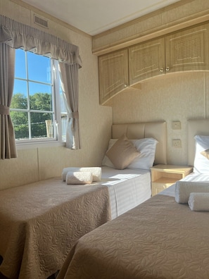 Classic bedroom with two single beds, decorative pillows, and a large window with storage above.