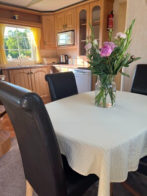 Enjoy meals in this kitchen with a dining table for four, a modern refrigerator, and a fire extinguisher for safety.
