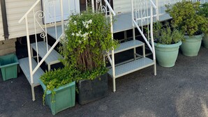 A mobile home with a front door open, a small porch with steps, and potted plants. - Heavenly Retreat - spacious & peaceful with patio (Ciliau Aeron)