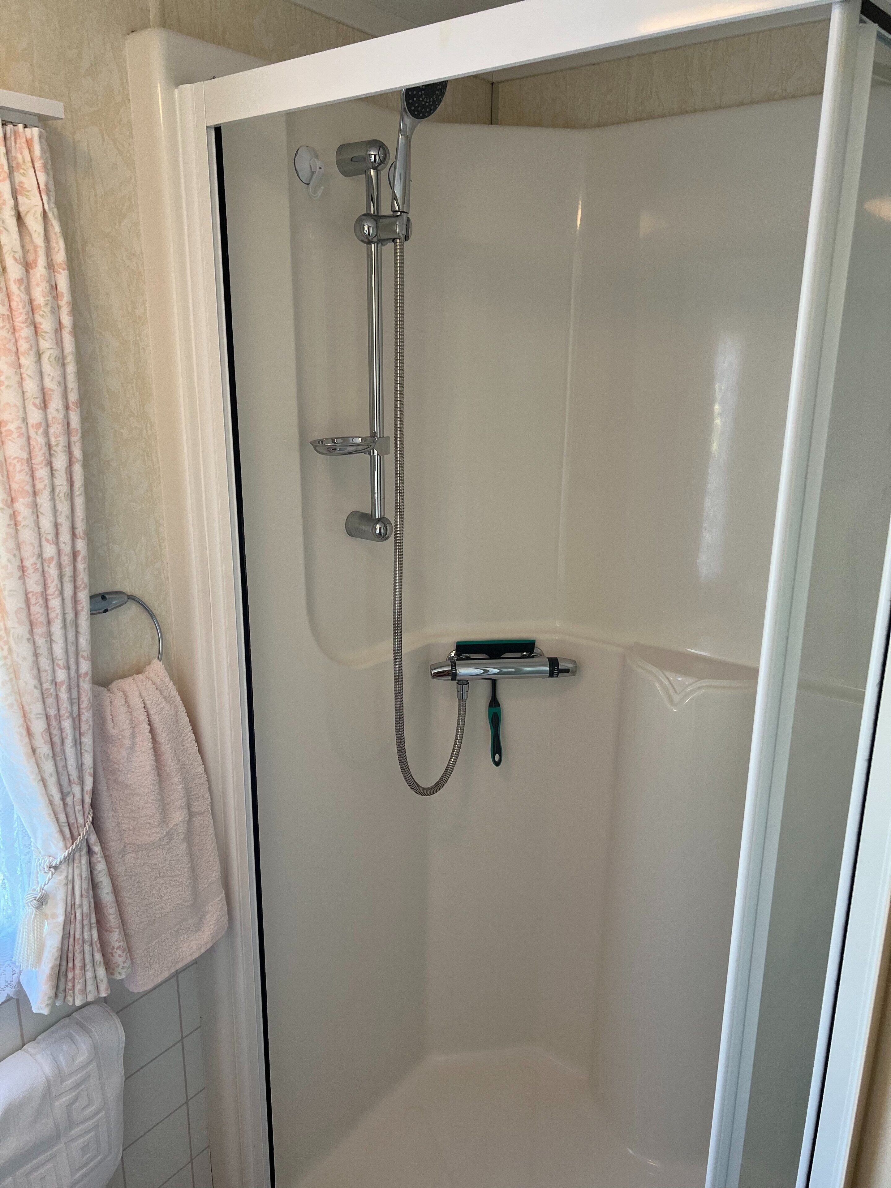 Ducha con paredes de vidrio, cabezal de ducha de mano y accesorio de ducha manual.