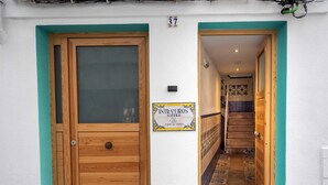 A wooden door with a glass panel, a sign reading "INTRAMUROS SUITES," and a staircase leading to an upper floor. - Peniscola Intramuros Suites (Peñíscola)