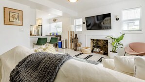 Un salon moderne avec une cheminée, un téléviseur et un coin repas à l’arrière-plan.
