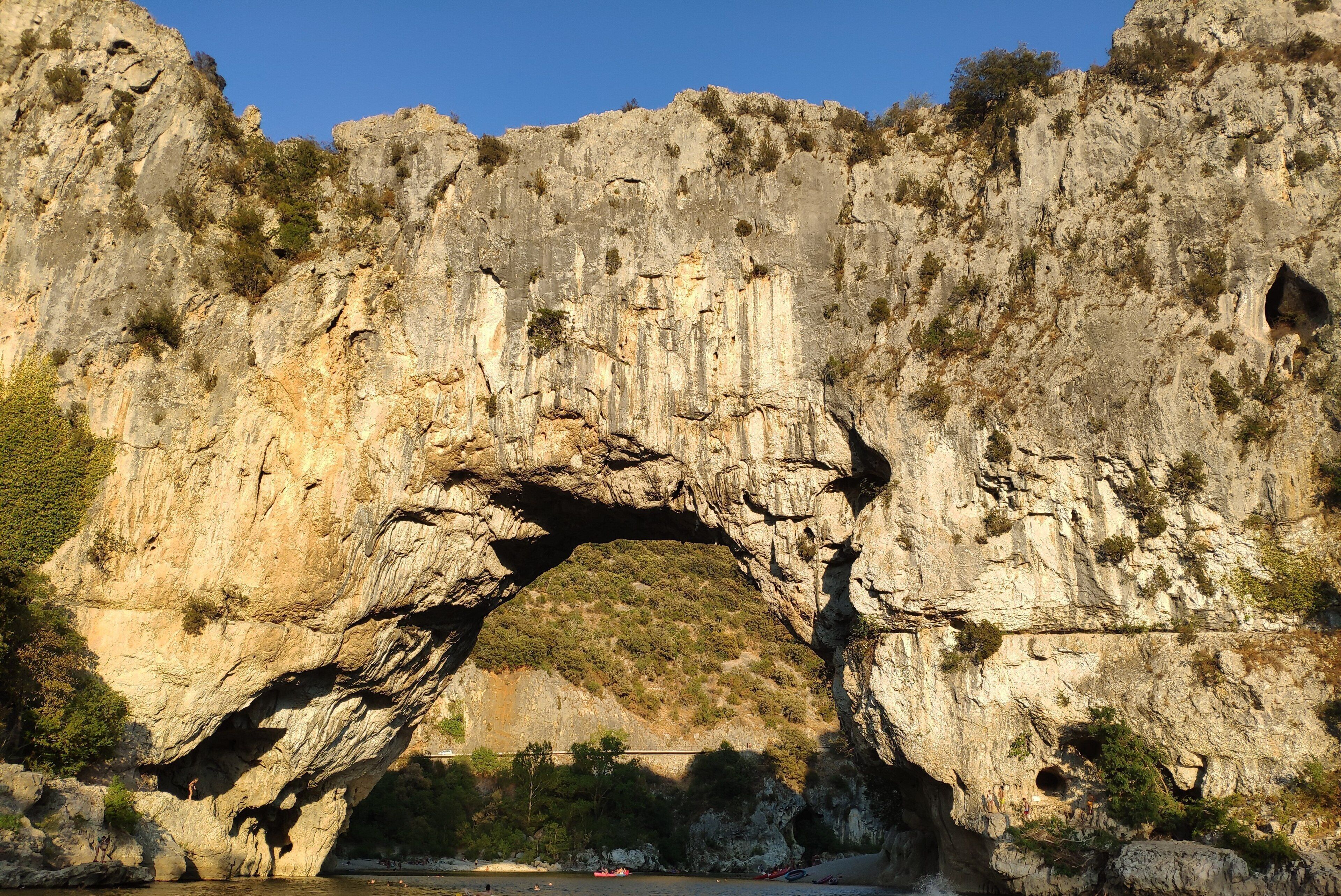 A natural rock arch formation with a river flowing beneath it.