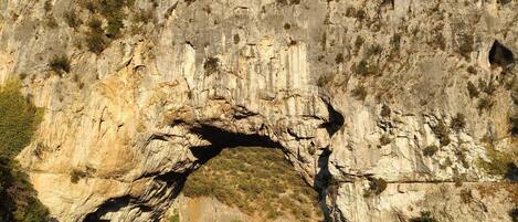 A natural rock arch formation with a river flowing beneath it.