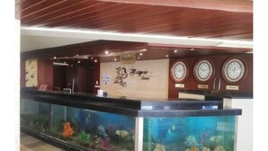 Un área de recepción con mostrador, un acuario grande y relojes en la pared.