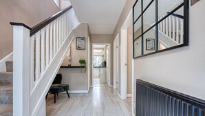 A hallway with a staircase, a radiator, and framed pictures on the walls. - Maple House (Solihull)