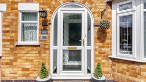 A brick house with a white front door, a small window, and a mailbox. - Maple House (Solihull)