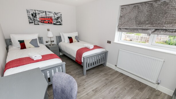 A bedroom with two beds, a window with a view, and a radiator. - Maple Lodge (Reading)