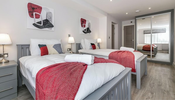 A hotel room with two beds, a desk, and a mirror.