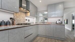 Una cocina moderna con armarios grises, encimera de mármol y cocina a gas empotrada.