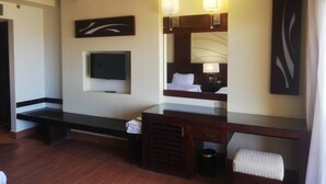 Una habitación de hotel con cama, televisor, escritorio y espejo.