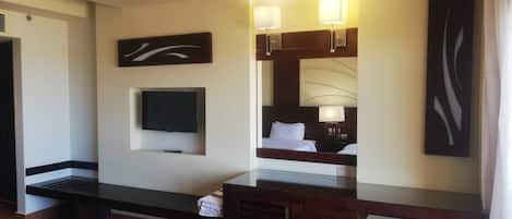 A hotel room with a bed, a TV, a desk, and a mirror.
