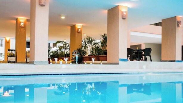 Una zona de piscina con un espacio de descanso, columnas y una mesa con sillas.
