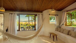 Una habitación con una hamaca, un sofá y vista a la playa.