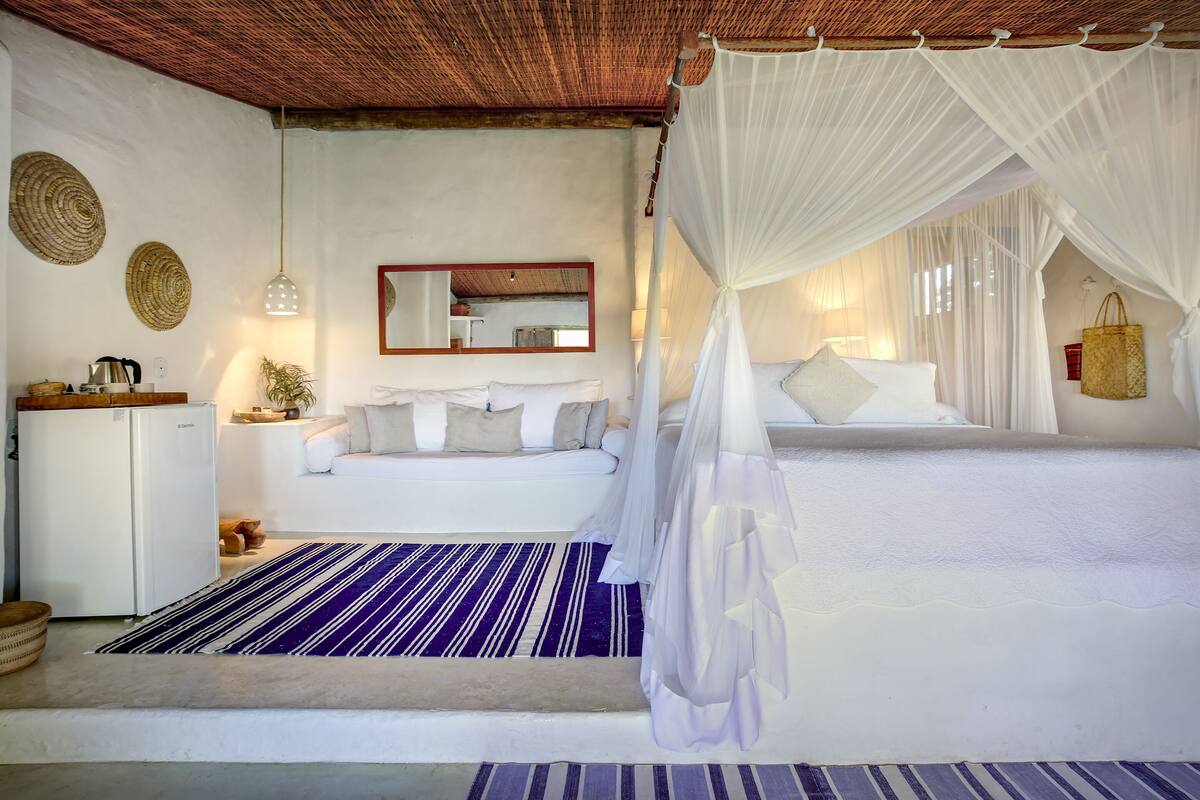 A bedroom with a bed, a nightstand, a mirror, and a hanging light fixture.