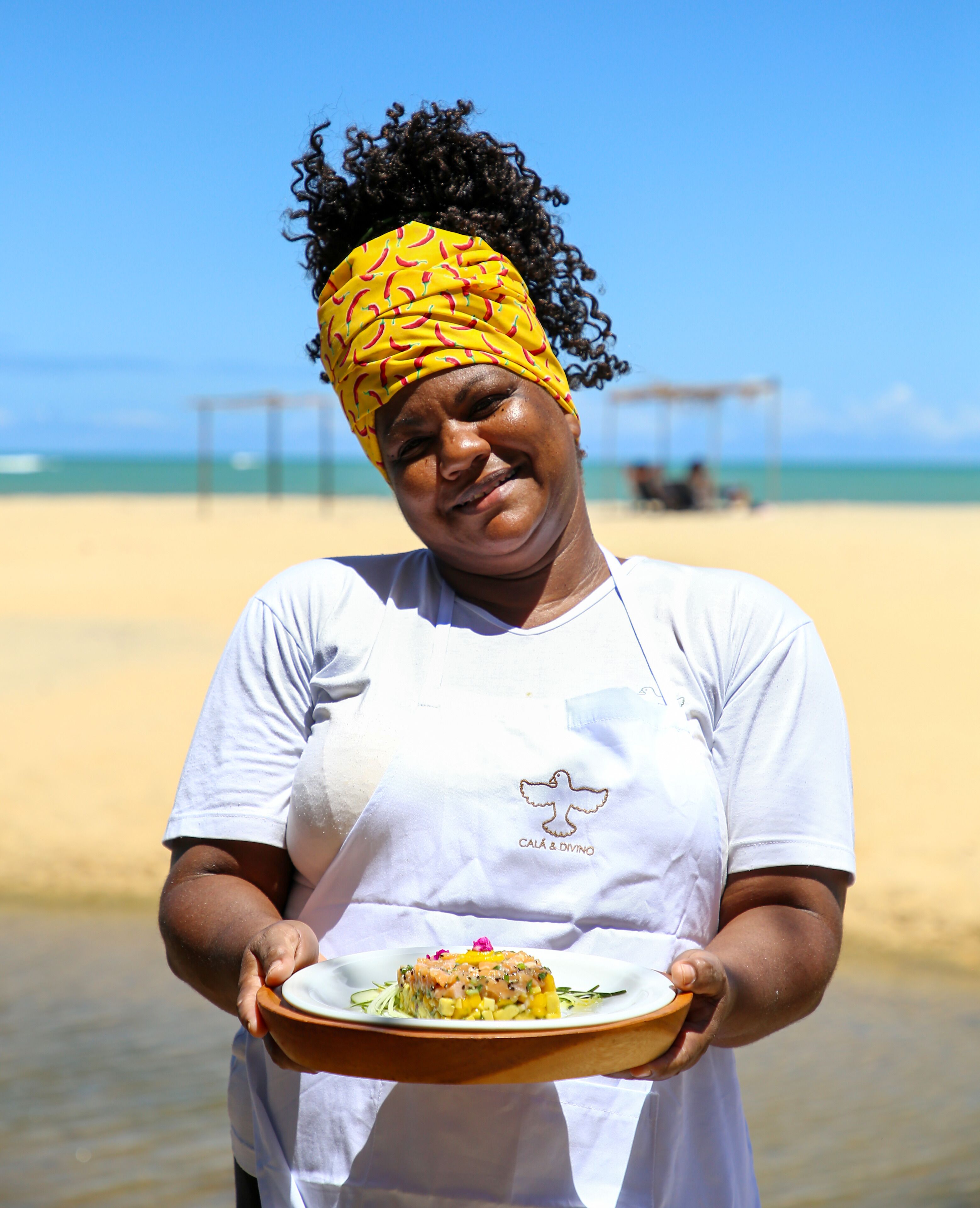 A person holding a plate with food on a beach.