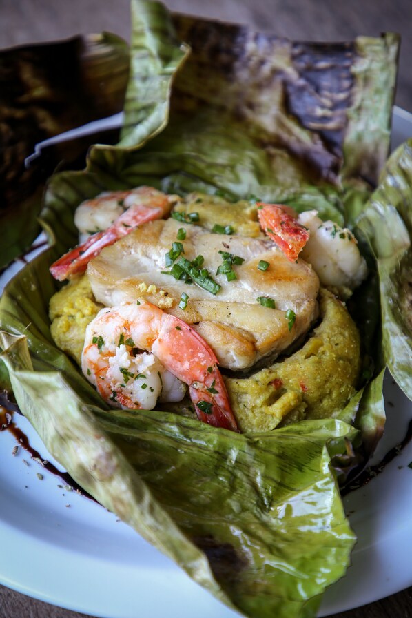 Un plato de mariscos con camarones y pescado sobre una cama de lechuga.