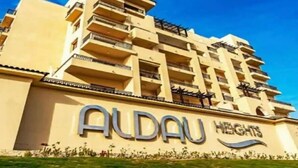 A multi-story hotel named 'Aldau Heights' with balconies and a clear sky.
