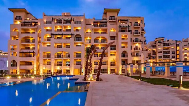 A multi-story hotel with a swimming pool in the foreground.