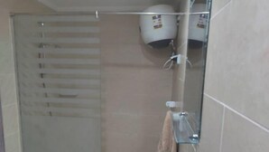 A bathroom with a glass shower enclosure, a white sink, and a towel rack.