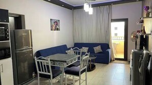 A compact living space with a kitchenette, a dining area, and a sofa. - Luxury Apartment in ALDAU HEIGHTS 10204 (Hurghada)