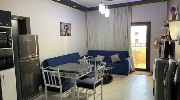 Un espacio habitable compacto con kitchenette, comedor y sofá.