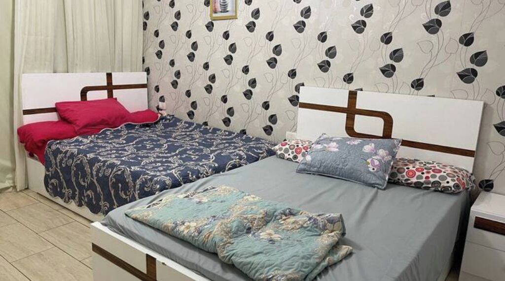 A room with two beds, each with a distinct patterned bedspread.