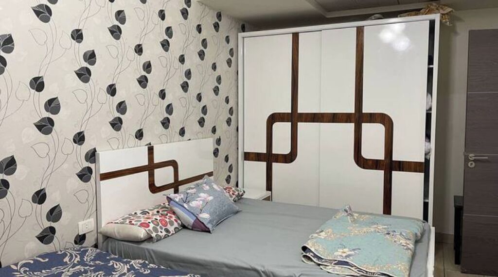 A bedroom with a bed, a wardrobe, and a patterned wall.