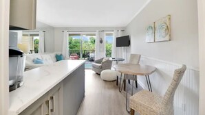 Eine moderne Küche mit weißer Arbeitsplatte, einem eingebauten Backofen und einem Essbereich mit rundem Tisch und Korbstühlen.