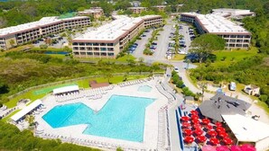Eine Vogelperspektive eines Hotels mit großem Schwimmbad, mehreren Gebäuden und einem Parkplatz.