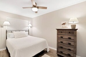 A bedroom with a bed, bedside lamps, a dresser, a ceiling fan, and a framed picture on the wall. - 3 min walk to Folly Field Beach Modern & Fun 1bdrm (Hilton Head Island)