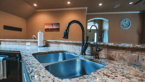 Eine Küche mit Granit Arbeitsplatten, Edelstahlspülen und einem schwarzen Wasserhahn.