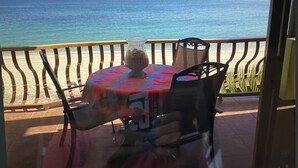 Un balcón con mesa y sillas con vista a la playa.