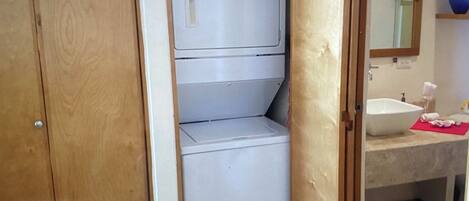 A compact laundry room with a built-in washer and dryer, a sink, and a mirror above the sink.