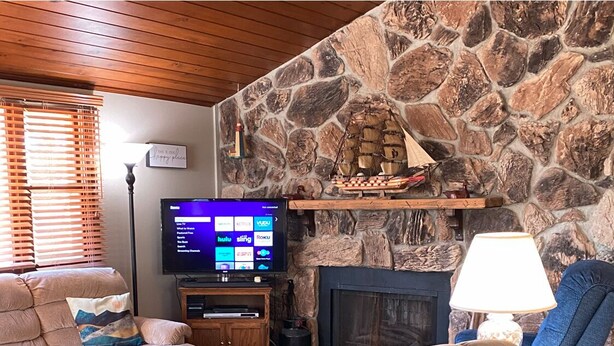 Una sala de estar acogedora con chimenea de piedra, televisor de pantalla plana y asientos cómodos.
