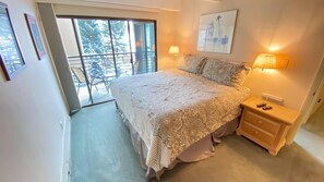 Relax in a serene bedroom with a large bed, sliding glass door to an outdoor area, and framed artwork on the walls.