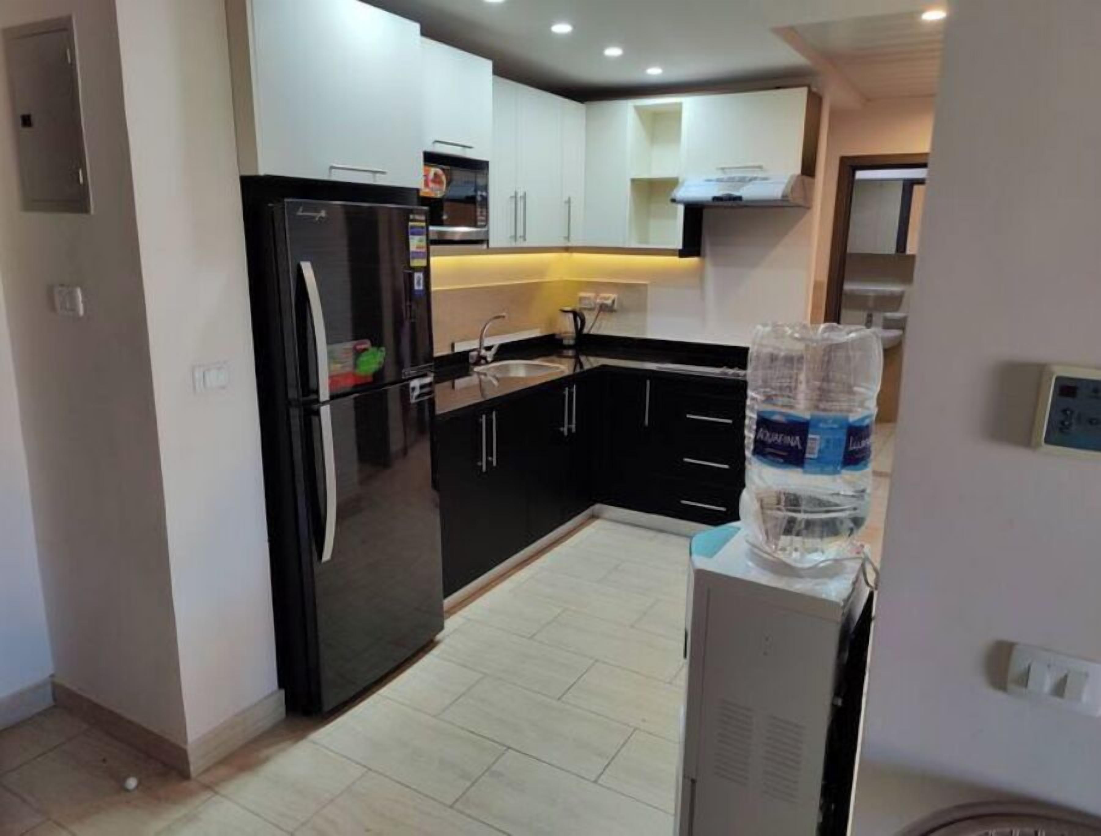 Una cocina compacta con refrigerador, lavamanos y armarios.