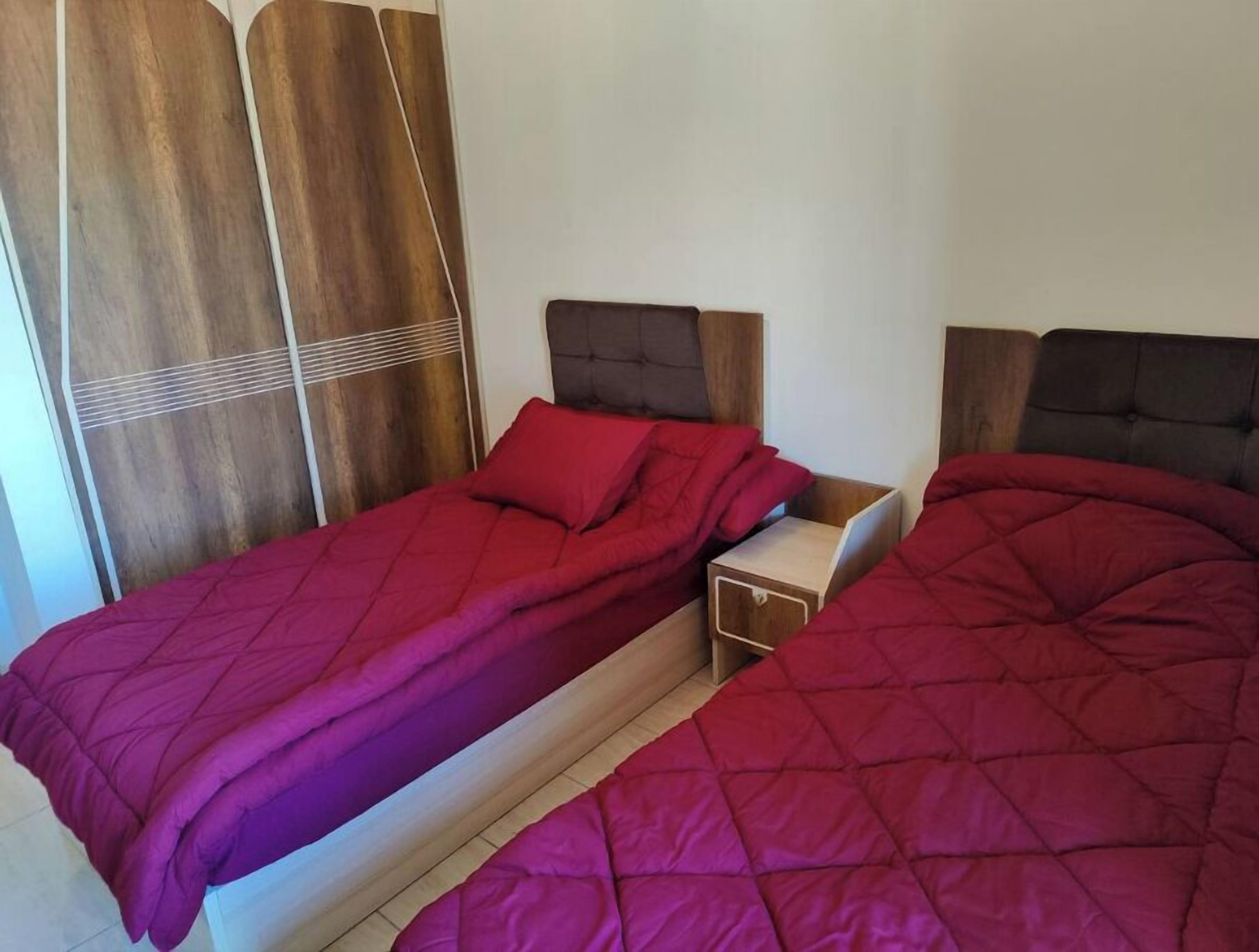 Ein Schlafzimmer mit zwei Betten, jeweils mit einer roten gesteppten Bettdecke und passenden Kissen.