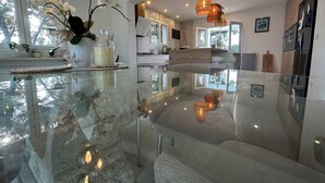 A modern kitchen with a glass-top island, white cabinetry, and a view of the outdoors.