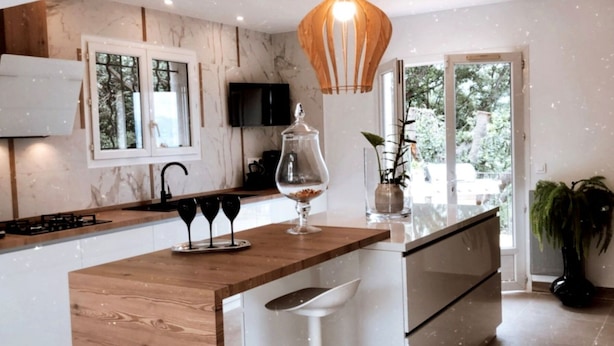 A modern kitchen with a wooden countertop, a built-in stove, a TV, and a large window.