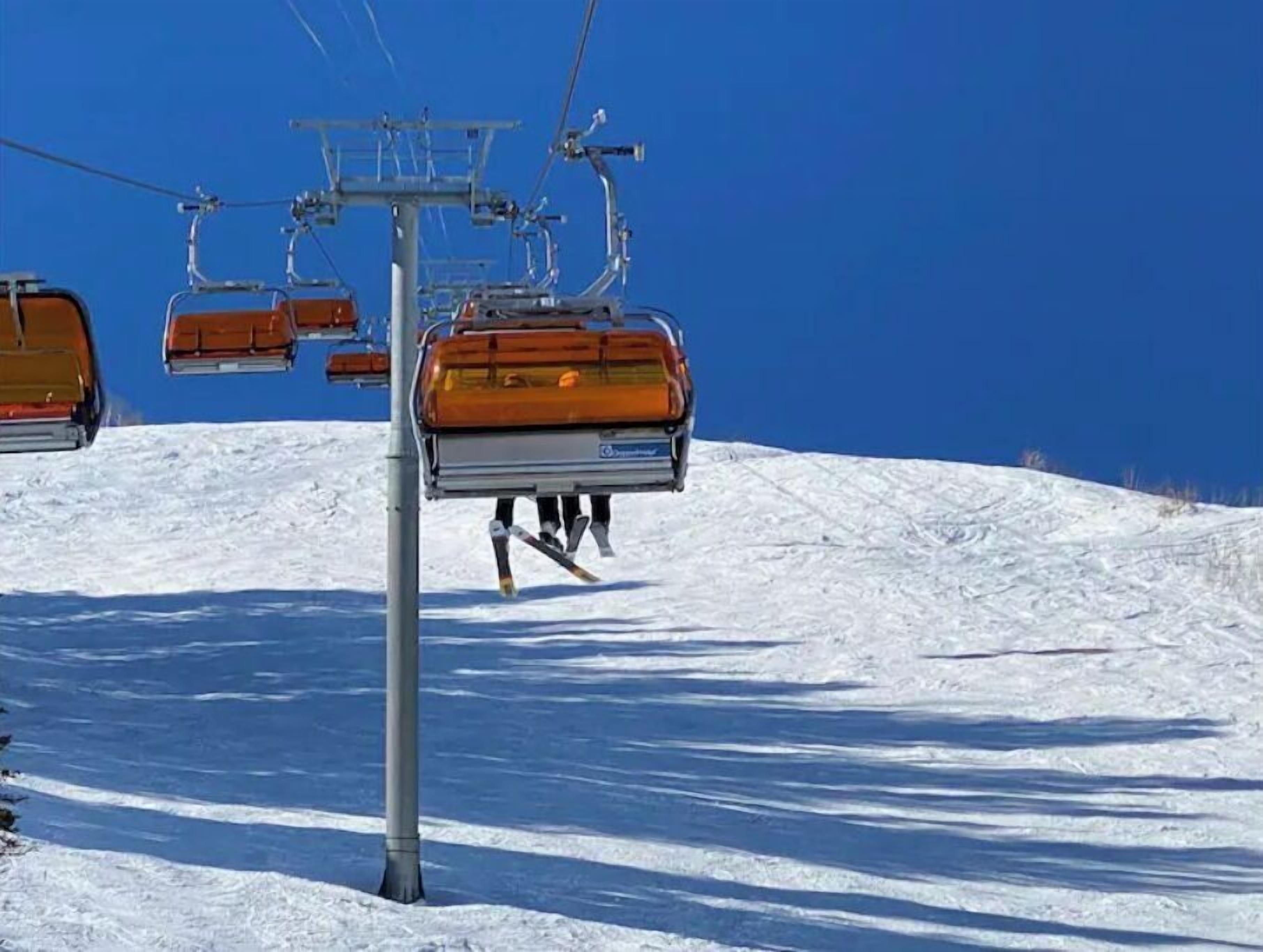 Un télésiège avec un poteau métallique, et un ciel bleu clair en arrière-plan.
