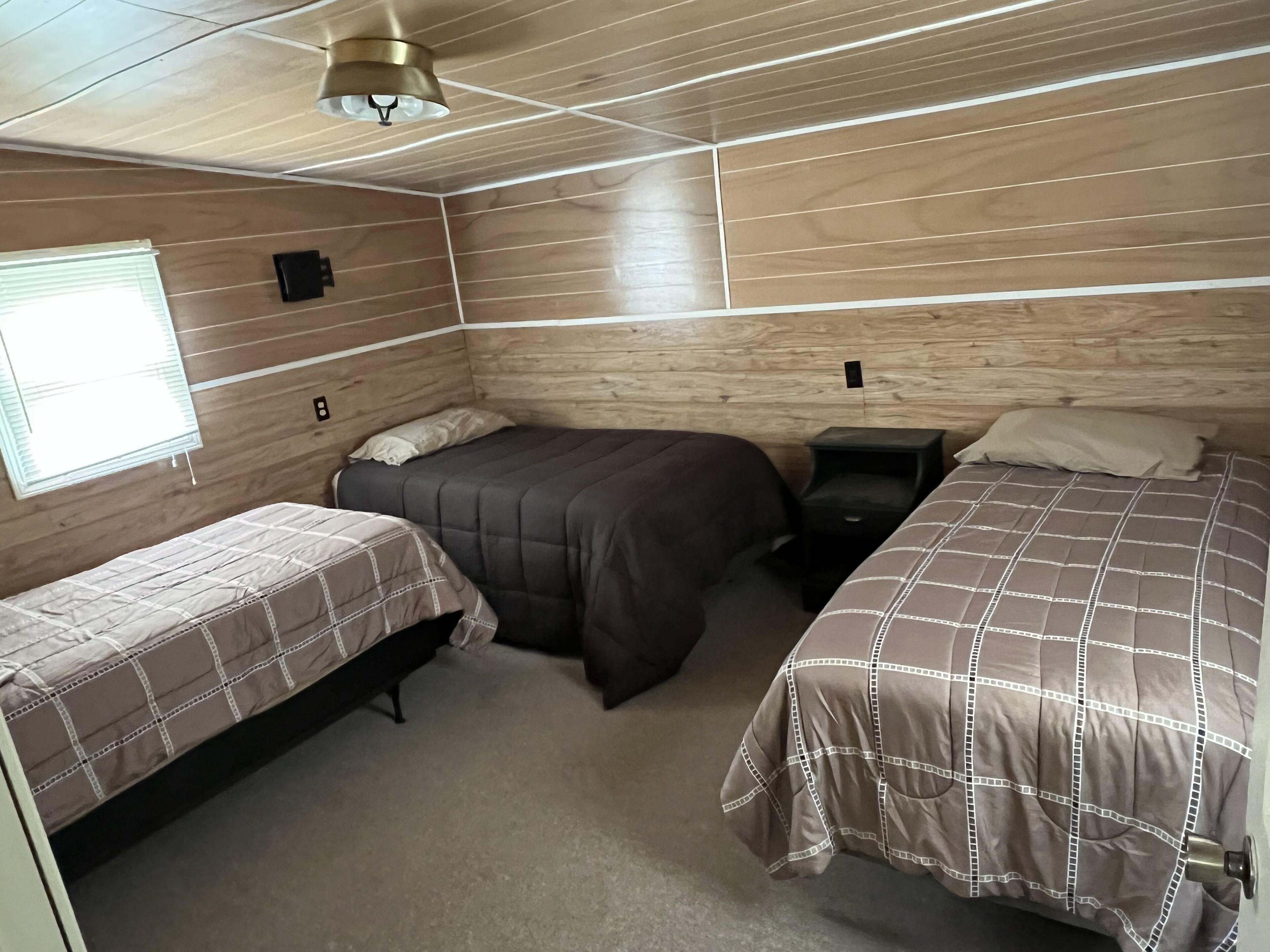 Una habitación con dos camas, una ventana y un ventilador de techo.
