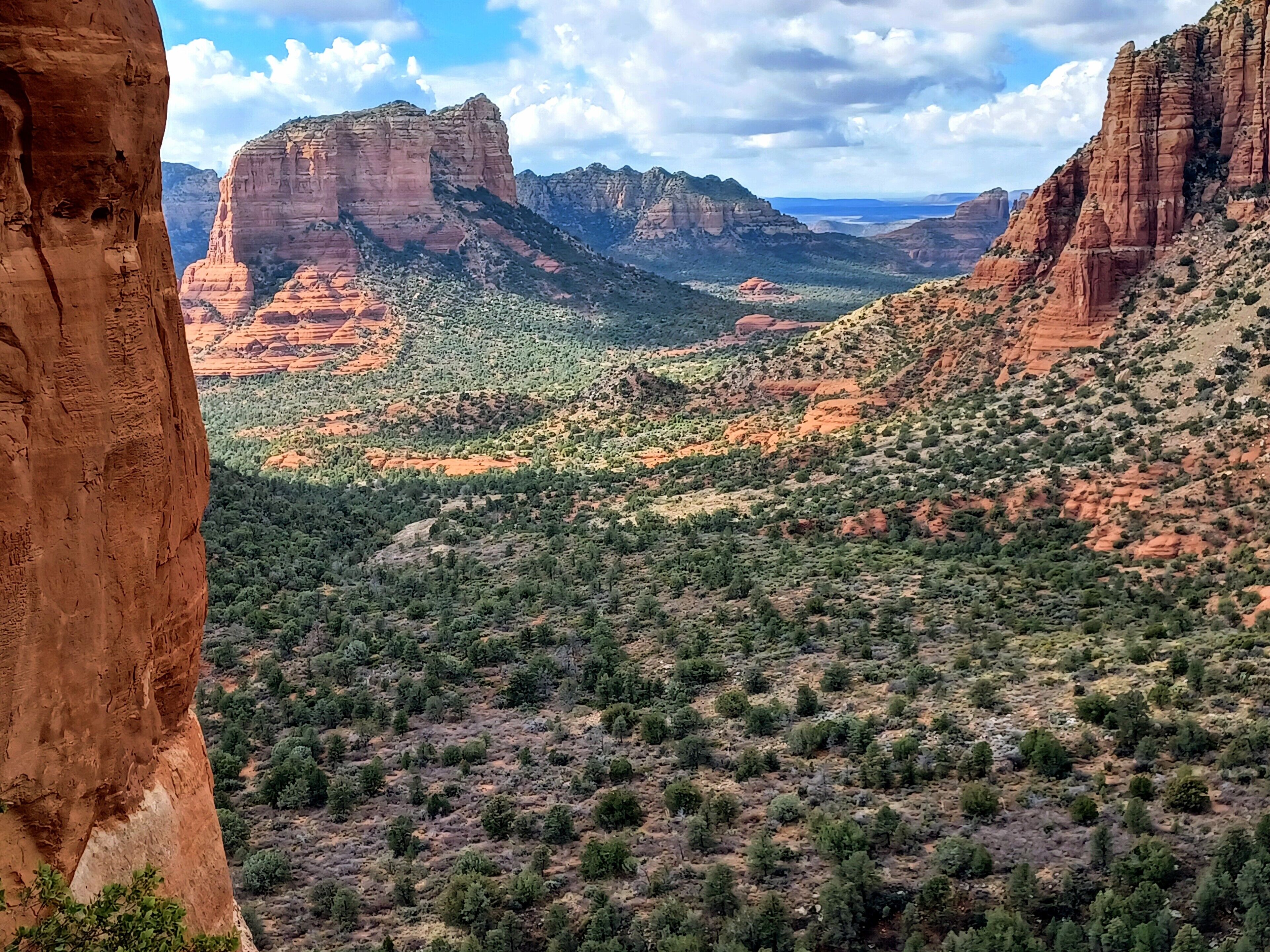 A mountainous landscape with red rock formations and green vegetation.
