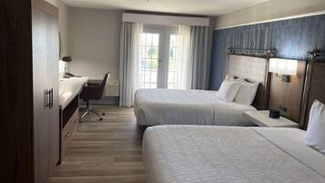 Een hotelkamer met twee bedden, een bureau en een stoel.