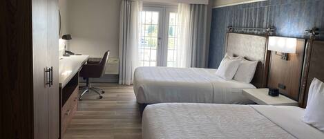 Una camera d'albergo con due letti, una scrivania e una sedia.