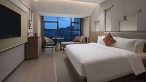 A modern hotel room with a large bed, a TV, a desk, and a view of the cityscape. - Days Hotel by Wyndham Chenzhou Beihu (Chenzhou)