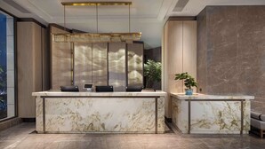 A reception desk with a marble top, two black chairs, a potted plant, and a modern chandelier. - Days Hotel by Wyndham Chenzhou Beihu (Chenzhou)