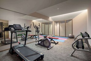 Une salle de sport moderne équipée de machines de cardio, d’appareils de musculation et dotée d’un mur entièrement recouvert de miroirs.