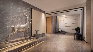 A modern lobby with a marble floor, a large sculpture of a deer, and a reception area with a wooden door. - Days Hotel by Wyndham Chenzhou Beihu (Chenzhou)