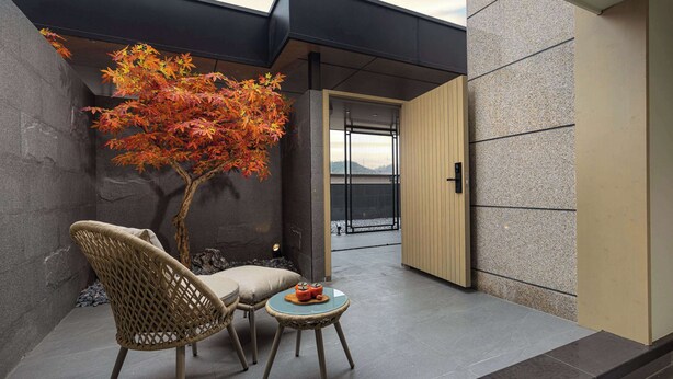 A modern outdoor seating area with a stone wall, a wooden door, and a view of the city. - Days Hotel by Wyndham Chenzhou Beihu (Chenzhou)